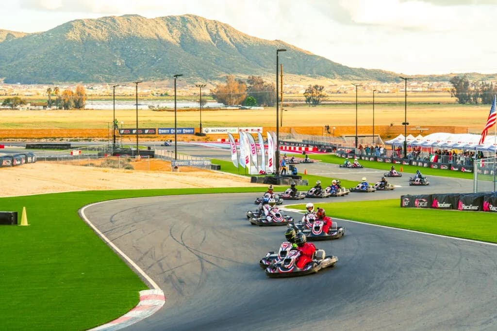 Rental karts racing through a daytime corner at K1 Circuit Winchester below the hills
